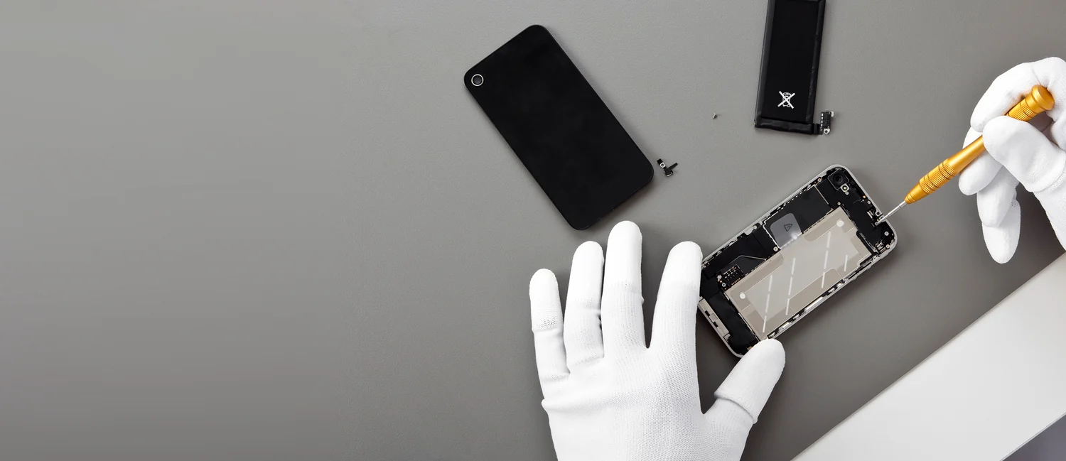Gloved hands carefully repairing a smartphone